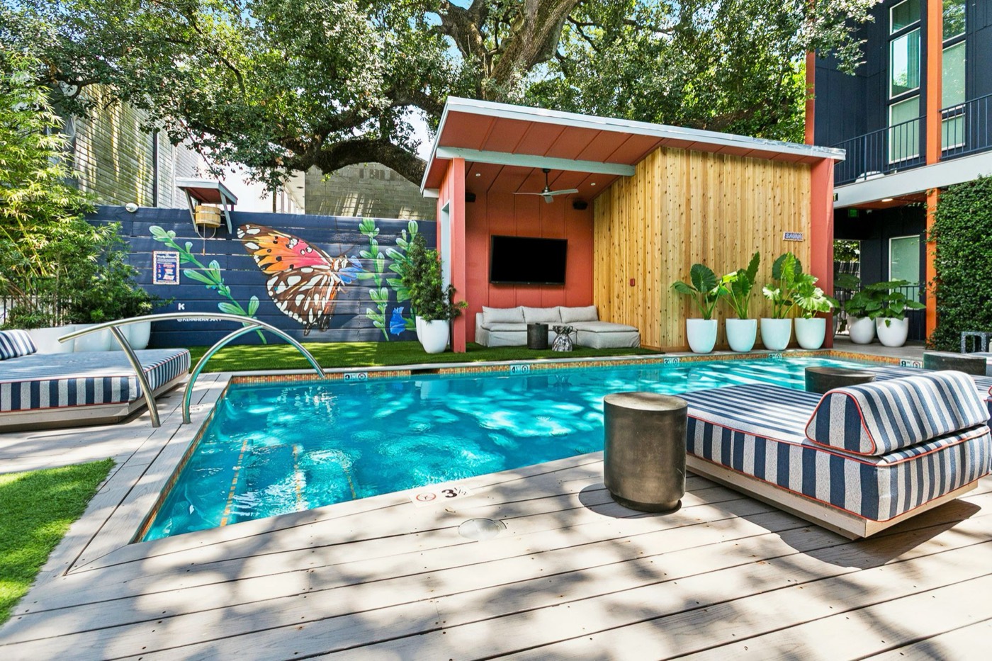The Syd's courtyard pool with striped loungers, butterfly mural, and TV cabana